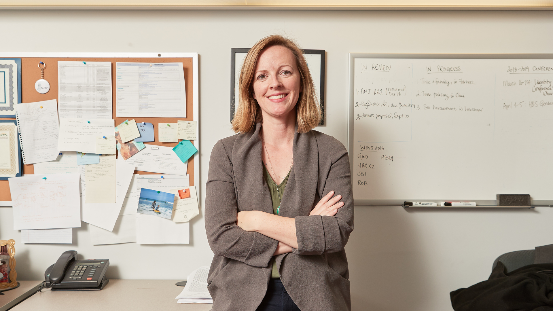Erin Reid, a smiling White woman folding her arms, wearing a light brown blouse.