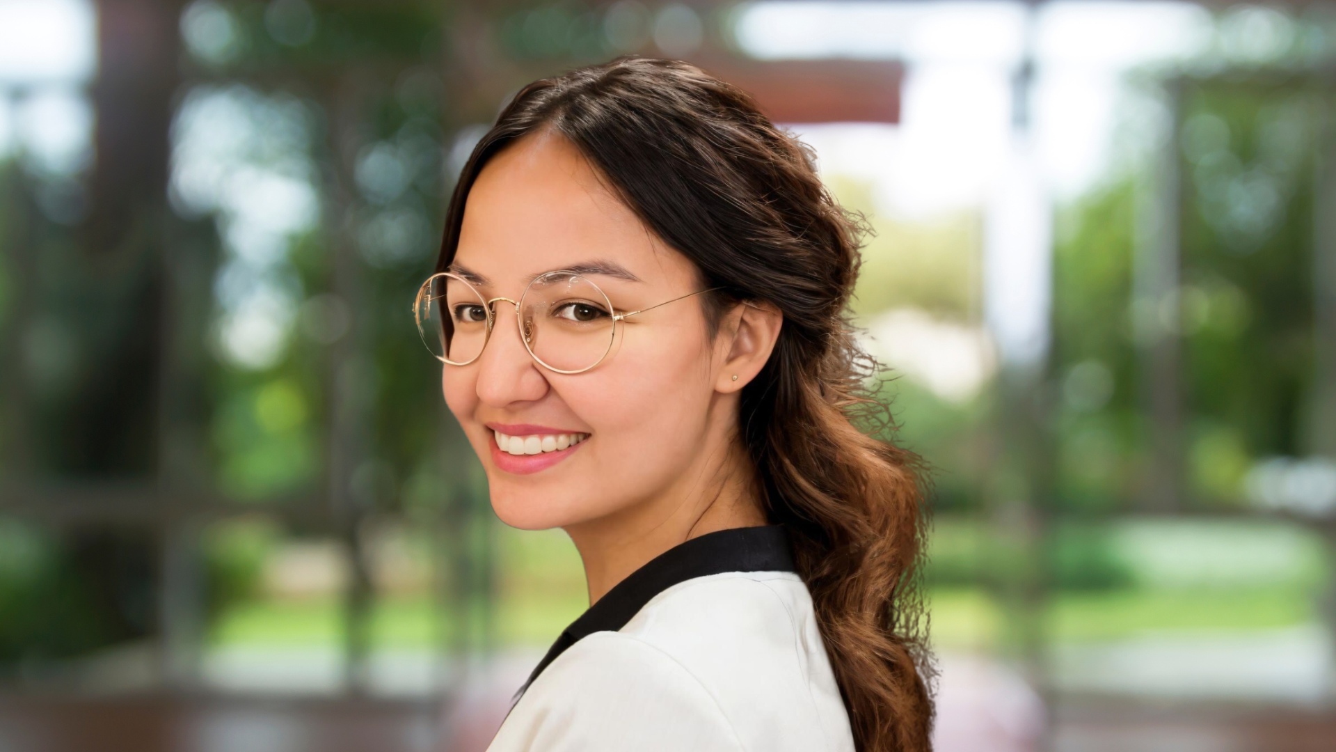 Portrait of Kaella-Marie Earle, a smiling Indigenous woman wearing glasses and a white jacket and black blouse.