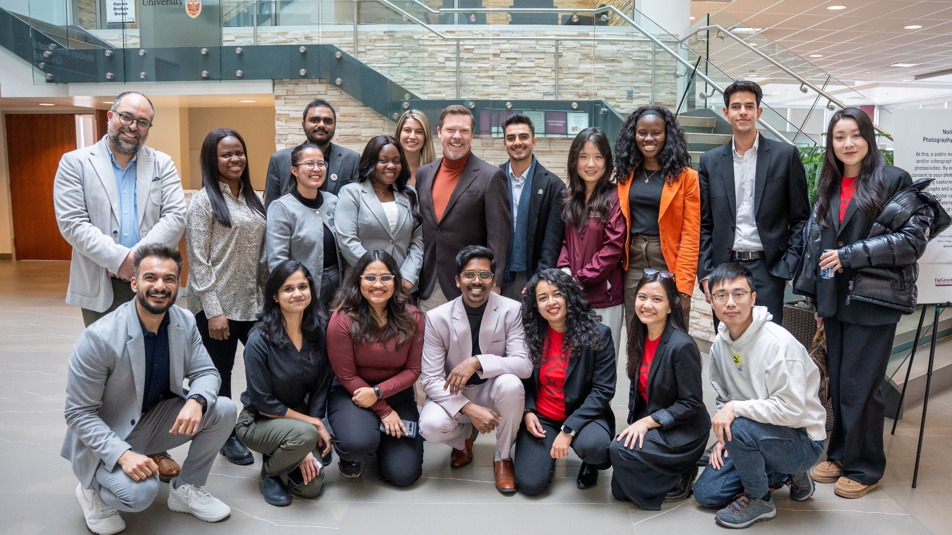 Group of participants posing together in an indoor atrium during GRIT Week.
