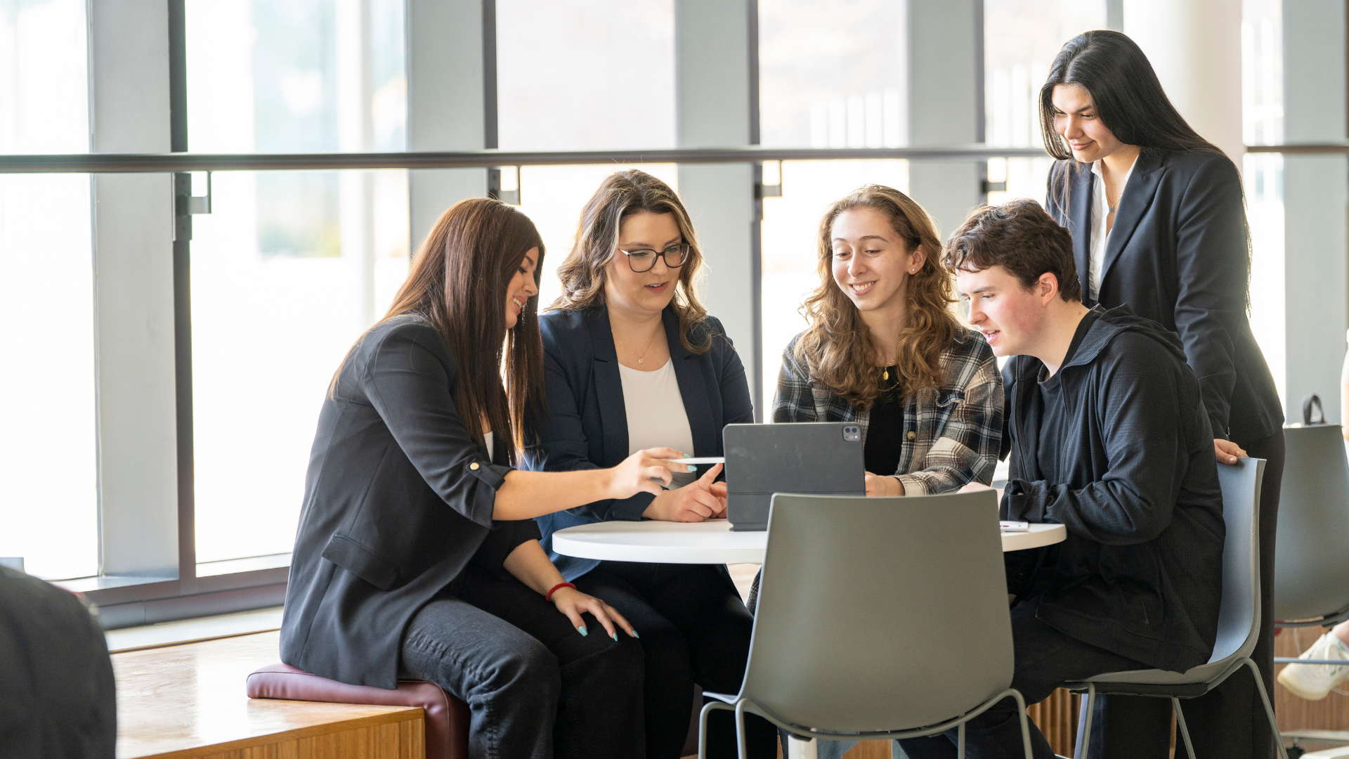 Group collaborating around a table with a laptop in a bright, modern workspace.