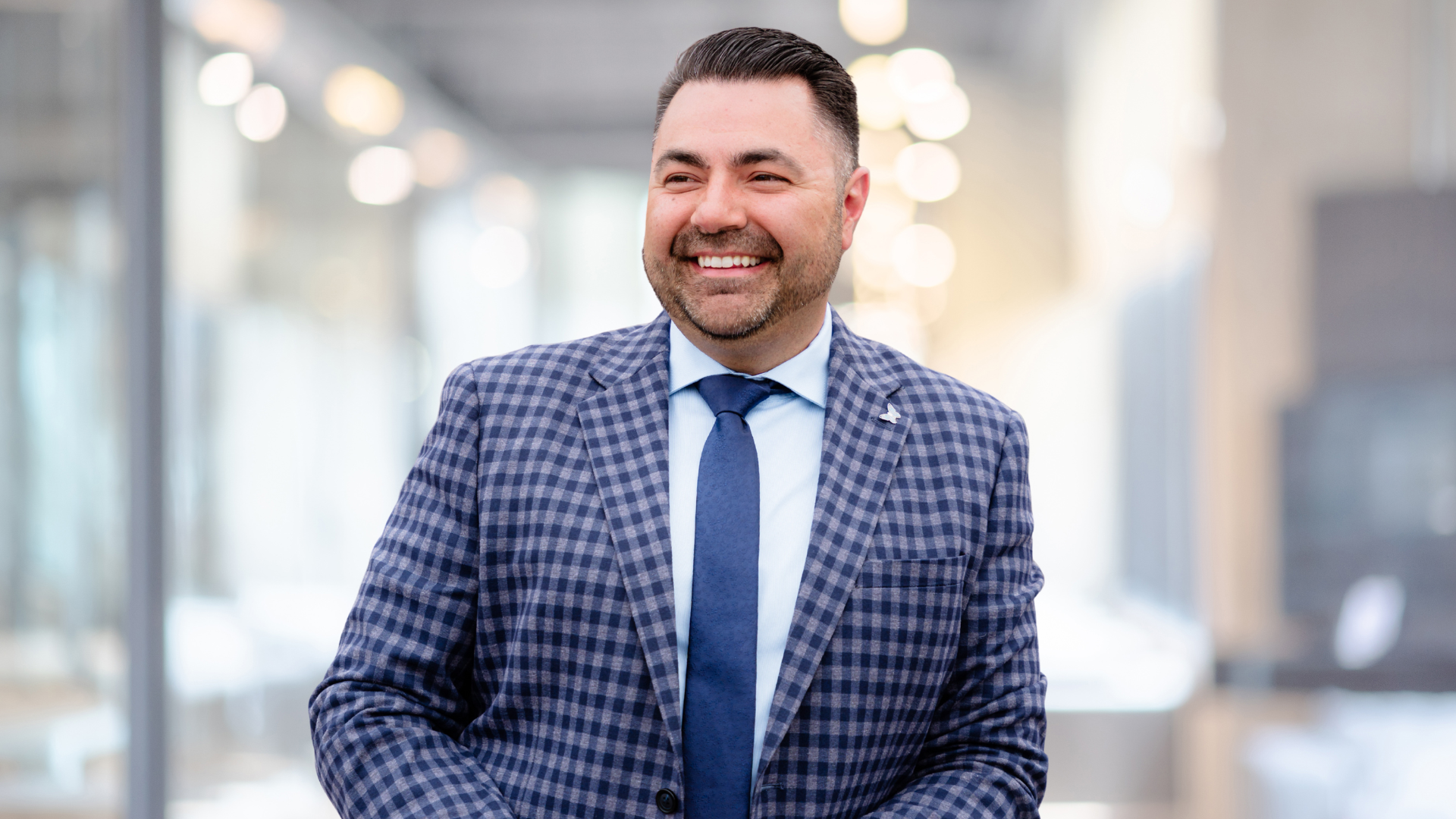 Headshot of a person in a checked suit and tie.